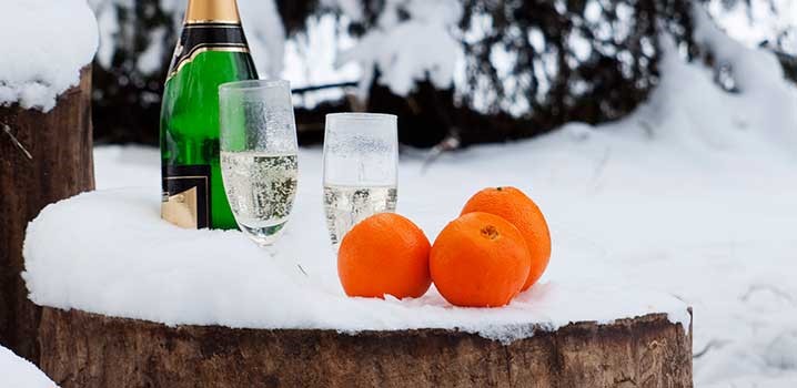 Champagne og appelsiner på en træstub i sneen